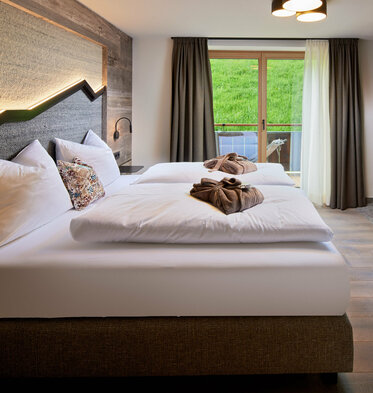 Schlafzimmer mit Doppelbett, Fernseher und Balkonzugang im Mei.Auszeit Appartement