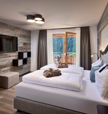 Schlafzimmer mit Doppelbett, Fernseher und offener Balkontür im Mei.Rückzug Appartement