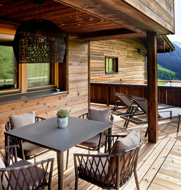 Balkonecke mit kleinem Esstisch, Sonnenliegen und Sonnenschirm