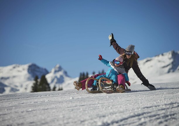 Frau mit Kleinkind beim Rodeln